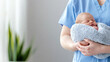 © Ari - Brunette nurse doctor woman carrying a newborn baby at pediatric home care healthcare