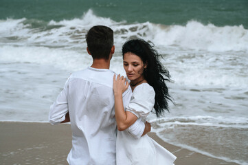 young beautiful couple in love hugging on the beach by the sea in summer