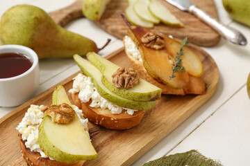 Wall Mural - Tray of pear bruschetta with ricotta cheese, walnuts and bowl of honey on white wooden background, closeup