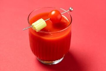 Wall Mural - Glass of bloody mary garnished with celery and tomato on red background