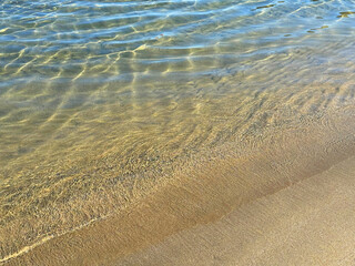 Wall Mural - Gentle ocean waves on sand beach.