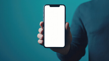 Wall Mural - A man in a blue sweatshirt is holding a mobile phone with a white blank screen. A mockup of the phone on a blue background. Mobile app ads, discounts, promotions