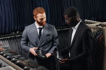 Wall Mural - Seller of shoes in store helping of man in suit buy leather footwear