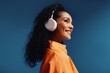 © Jacob Lund - Woman wearing headphones in a vibrant orange and blue monochromatic studio setting, smiling and enjoying music