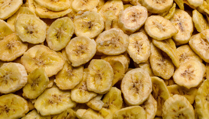 Fototapete - Repeating pattern of dried banana chips, highlighting their crispy texture and golden-yellow color. Ideal for healthy snacks, tropical, or natural food concepts. Texture, background.