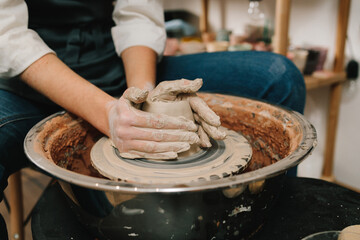 Poster - Female potter forms a clay product on a potter's wheel. Process of sculpting ceramic crockery in the manufacturing.
