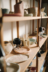 Poster - Shelf with handmade clay cups and plates in the pottery studio. Creating ceramics ware with own hands.