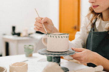 Fototapete - Painter is drawing and adding unique designs to the earthenware. Artist is decorating and painting handmade ceramic clay cup in the creative workshop.