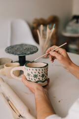 Poster - Design earthenware cup with a traditional pattern. Artist is making decoration on the clay ceramic mug after oven firing.