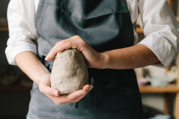 Poster - Potter holds a piece of wet clay in their hands, molds it into form. Process of creating ceramic products.