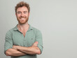 © Alienmonster Images - Confident Smiling Man with Beard and Casual Shirt Standing with Arms Crossed on Neutral Background