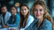 © NeuralStudio - A smiling Caucasian female doctor with stethoscope looking at the camera while colleagues are blurred in the background. She has long hair and a warm smile.
