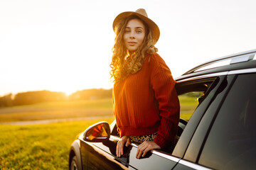 Wall Mural - Beauty woman enjoy in road trip in car at sunset. Full of joy. Lifestyle, travel, tourism, nature, active life