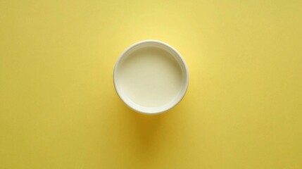 Poster - A coffee cup brimming with creamy liquid sits on a cheerful yellow surface. The bright color accentuates the inviting warmth of the drink, adding vibrancy to the cozy setting