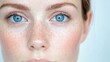 © яна винникова - Close-up portrait of a young woman showcasing her striking blue eyes and freckles against a light background
