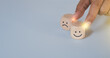 © LAONG - Hand holding wood cube with smile icon, World mental health day or feedback rating concept, Positive customer review, Wood cube stacking with emotion face icon on blue background