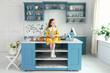 © stock_studio - Little Girl playing with easter bunny. Young girl sit on kitchen with easter cake, decorations, spring flowers, easter eggs and bunny. Child Girl in yellow dress holding toy easter rabbit in hands.