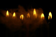 © alexkich - Row of Illuminated Candles with Smoky Background in Low Light Setting
