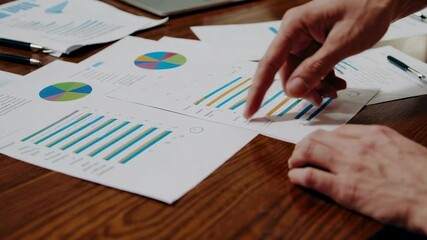 Poster - Business team analyzing marketing data in slow motion during a corporate meeting, pointing at charts and pie graphs placed on a wooden table