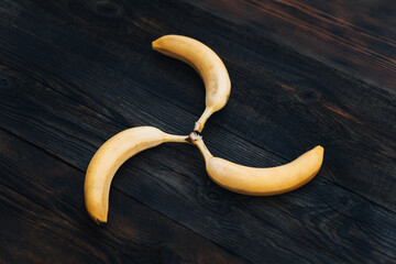 Wall Mural - Three bananas lie on a wooden table, tasty and fragrant fruits. Bananas on brown wooden table top view. Figured position of bananas in geometric shape. bananas are laid out in the shape of the sun.