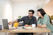 © Wosunan - Portrait of a young freelancer smiling while working online via laptop at home with his girlfriend