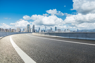 Wall Mural - empty highway road leads to the city skyline under blue sky