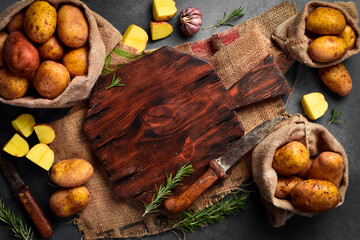 Wall Mural - Background Cooking dishes from potatoes. Fresh potatoes, kitchen cutting board, knife and spices. On a wooden background. Free space for text.