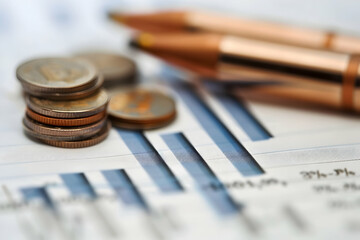 Poster - Close-up of coins and pens on financial charts illustrating investment analysis trends