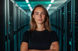 © designermetin - Confident young female it specialist standing in modern data center with server racks and cybersecurity technology environment