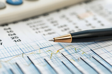 Poster - Close-up of a pen resting on financial charts with a calculator in the background, indicating analysis
