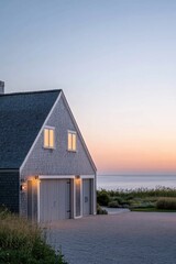 Wall Mural - A stunning coastal house bathed in warm lighting at sunset, beautifully complemented by a tranquil ocean backdrop, creating a serene and peaceful close to the day