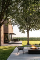 Wall Mural - Serene outdoor living space with modern furniture positioned near a fire pit surrounded by lush greenery and a spacious view of a field at sunset