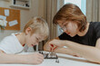 © looking2thesky - A loving mother and her son play chess together in a cozy home setting. The boy, wearing a hearing aid, focuses on the game with excitement. A heartwarming moment of parenting, bonding, and childhood