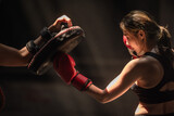 Portrait young Muay Thai boxer woman training elbow fighting on pads with trainer 