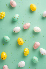 Wall Mural - easter vertical eggs in different colors and patterns spread on a green background