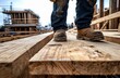 © MilaK K - Close-up of a construction worker's sturdy boots standing on wooden planks at an active building site
