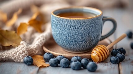 Canvas Print - A minimalistic setup featuring a blue cup of honey and blueberries on a wooden surface with autumn leaves and a cozy knitted fabric