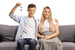© Ljupco Smokovski - Young couple sitting on a sofa and holding a home key