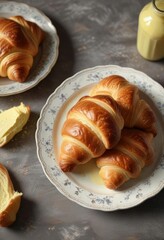 Wall Mural - Croissants arranged artfully on a decorative plate with a side of creamy butter , pastry, croissants