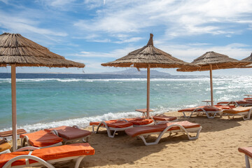 Poster - Relaxing beach view in Egypt with straw umbrellas and sun loungers by the serene blue sea