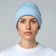 © justjupiter - A close-up portrait of a woman wearing a light blue beanie and a white sweater, displaying a neutral expression and clear blue eyes.