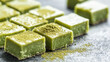 © Alla Bondaruk - Delicious green tea fudge squares dusted with matcha powder on a dark surface