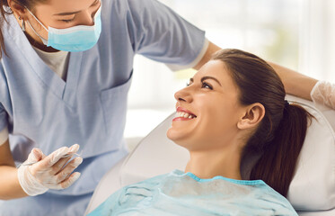 cheerful nurse or doctor orthodontist conducting an oral checkup on a happy female patient using den