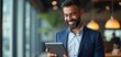 © Ada - Happy Latin Hispanic bearded stylish mature adult professional business man, smiling Indian senior businessman CEO holding digital tablet using fintech tab application standing inside company office