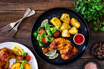 Wall Mural - Oven roasted chicken thigh with potatoes and fresh salad on wooden table