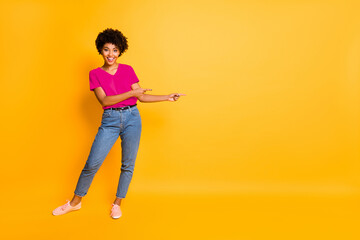 Wall Mural - Copyspace full length body size photo of nice charming pretty sweet girl black presenting you something proposing wearing t-shirt jeans denim isolated with yellow vivid color background