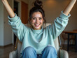 © Leonardo - Mujer joven sentada en un sillón moderno, levantando los brazos con entusiasmo, vestida con jeans y sudadera informales