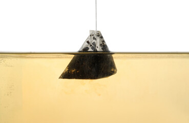 Wall Mural - Putting tea bag into glass cup on white background, closeup