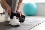 Woman putting on ankle weights in gym, closeup