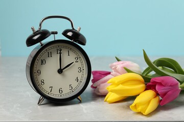 Aufkleber - Spring time. Alarm clock and beautiful tulips on grey marble table against light blue background